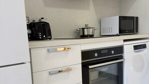 A modern kitchen with white cabinetry, a built-in microwave, a toaster, and a dishwasher.
