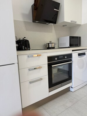 A modern kitchen with white cabinetry, a built-in microwave, a toaster, and a dishwasher.