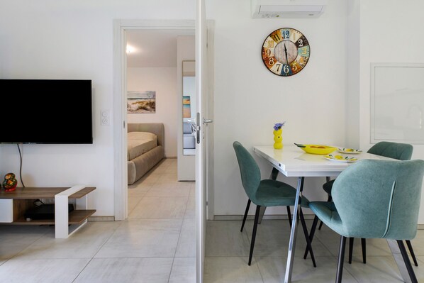 Un salon moderne avec un téléviseur à écran plat, une table à manger avec des chaises et une horloge murale.