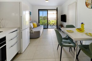 A compact kitchen with a dining area, a sofa, and a TV.