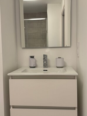 Une salle de bain avec un lavabo blanc, un miroir et des toilettes.
