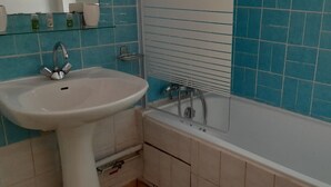 Casa de banho com lavatório branco, banheira e paredes revestidas de azulejos azuis.