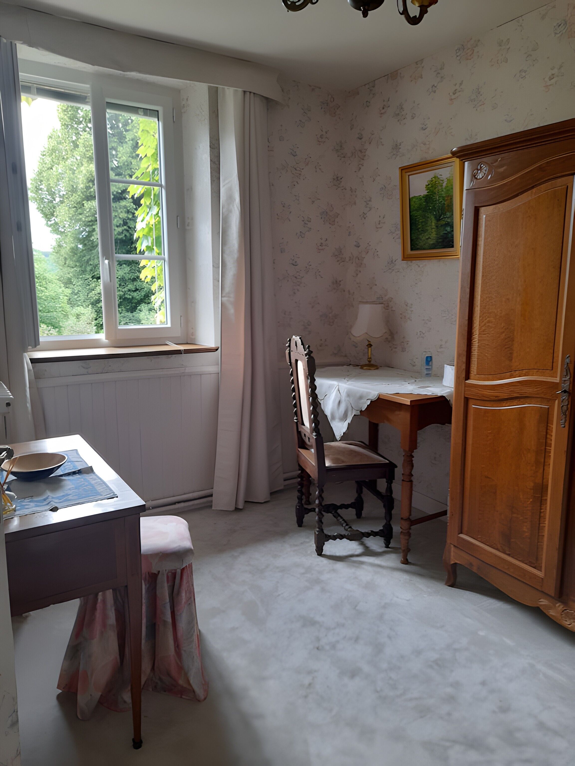 Een kamer met een raam, een bureau met stoel, een kast en een tafel met lamp.