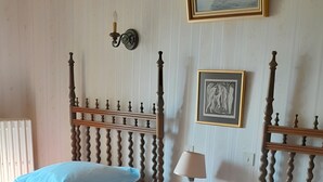 Quarto com duas camas, mesa de cabeceira, abajur e luminária na parede.