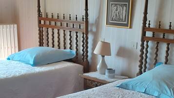 Une chambre avec deux lits, une table de chevet, une lampe et un luminaire fixé au mur.