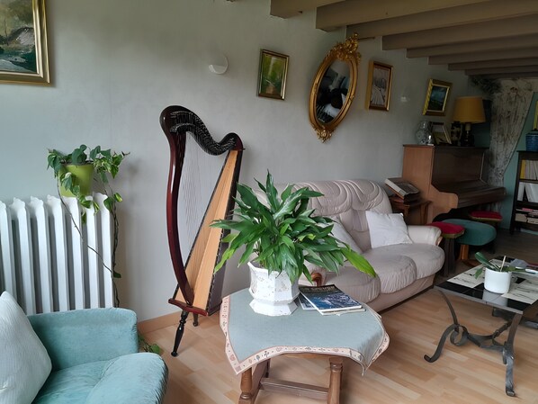 A living room with a harp, a sofa, a coffee table, and various framed pictures on the wall.