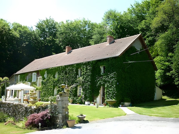 A house with a sloped roof, surrounded by lush greenery and a well-maintained lawn.