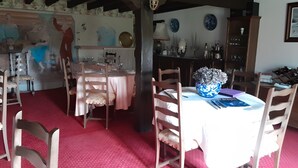 A dining area with a round table, chairs, a vase, and a wall with decorative plates. - Bed and Breakfast 'Domaine Des Mouillères - Julie' with Shared Terrace, Shared Garden and Wi-Fi (Saint-Georges-la-Pouge)