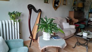 A living room with a harp, a sofa, a coffee table, and various framed pictures on the wall.