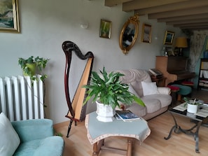 A living room with a harp, a sofa, a coffee table, and various framed pictures on the wall.