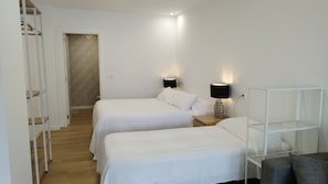 Habitación de hotel con dos camas, un armario, una mesita de noche y una lámpara.