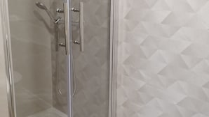 A glass-enclosed shower area with a showerhead and handheld shower attachment.