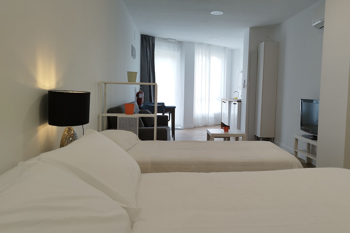 Una habitación de hotel con cama, escritorio, televisor y armario.
