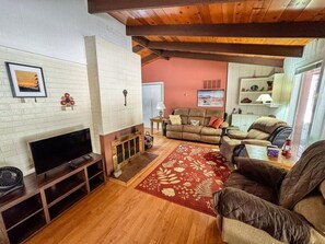 Una sala de estar con chimenea, un sofá, un televisor y una alfombra roja con estampado.
