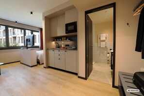 A modern kitchen with a built-in microwave, cabinets, and a window overlooking a residential area. - Ipartment Frankfurt Eastside @Home By Best Western (Frankfurt)