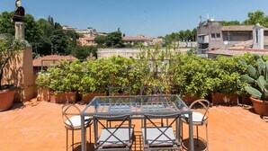 A terrace with a table and chairs, potted plants, and a statue.