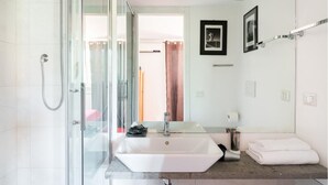 A modern bathroom with a glass shower enclosure, a white sink, and a large mirror.