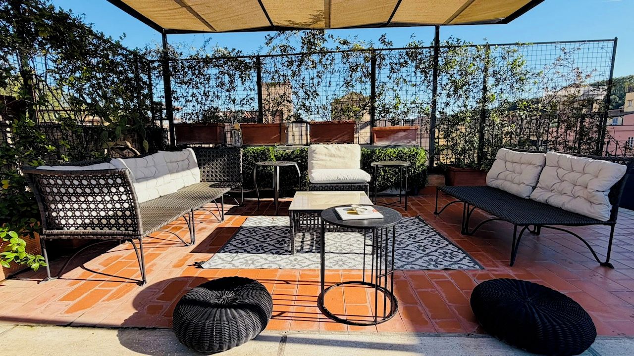 An outdoor patio with a covered seating area, including a sofa, chairs, and a table.
