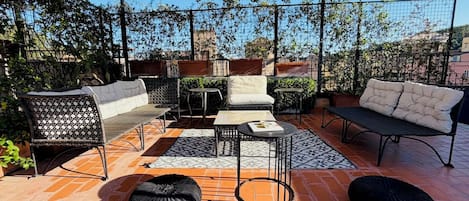 An outdoor patio with a covered seating area, including a sofa, chairs, and a table.