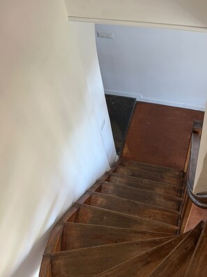 A wooden staircase with a white wall on one side and a tiled floor. - Penthouse in Trastevere (Roma)