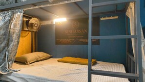 Een stapelbed met een ventilator, een kussen en een bordje met de tekst SinhaSaan hostel.