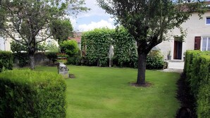 A well-maintained garden with a lawn, hedges, and a stone structure.