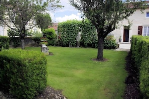 A well-maintained garden with a lawn, hedges, and a stone structure.