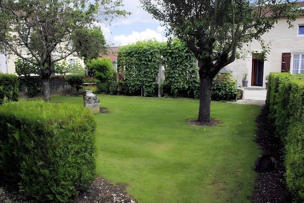 A well-maintained garden with a lawn, hedges, and a stone structure.