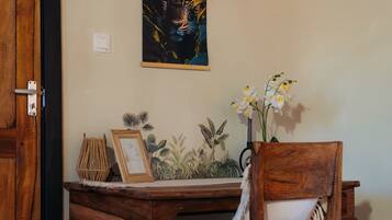 A wooden desk with a chair, a framed picture, and a wall-mounted painting.