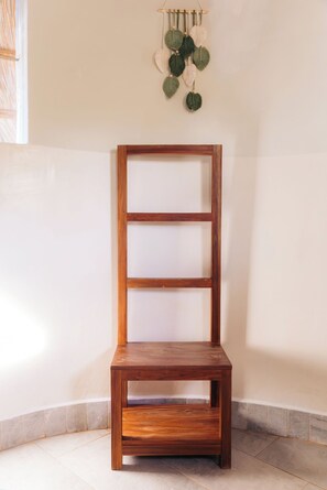 Una estantería de madera con tres repisas frente a una pared lisa.