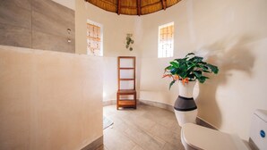 A bathroom with a tiled floor, a wooden chair, a white toilet, and a potted plant. - Romantic Villa , 2-Min Beach Walk -AC, Wifi (Pwani Mchangani)