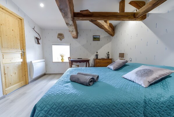 Une chambre à coucher avec un lit, une porte en bois, un bureau et une fenêtre.