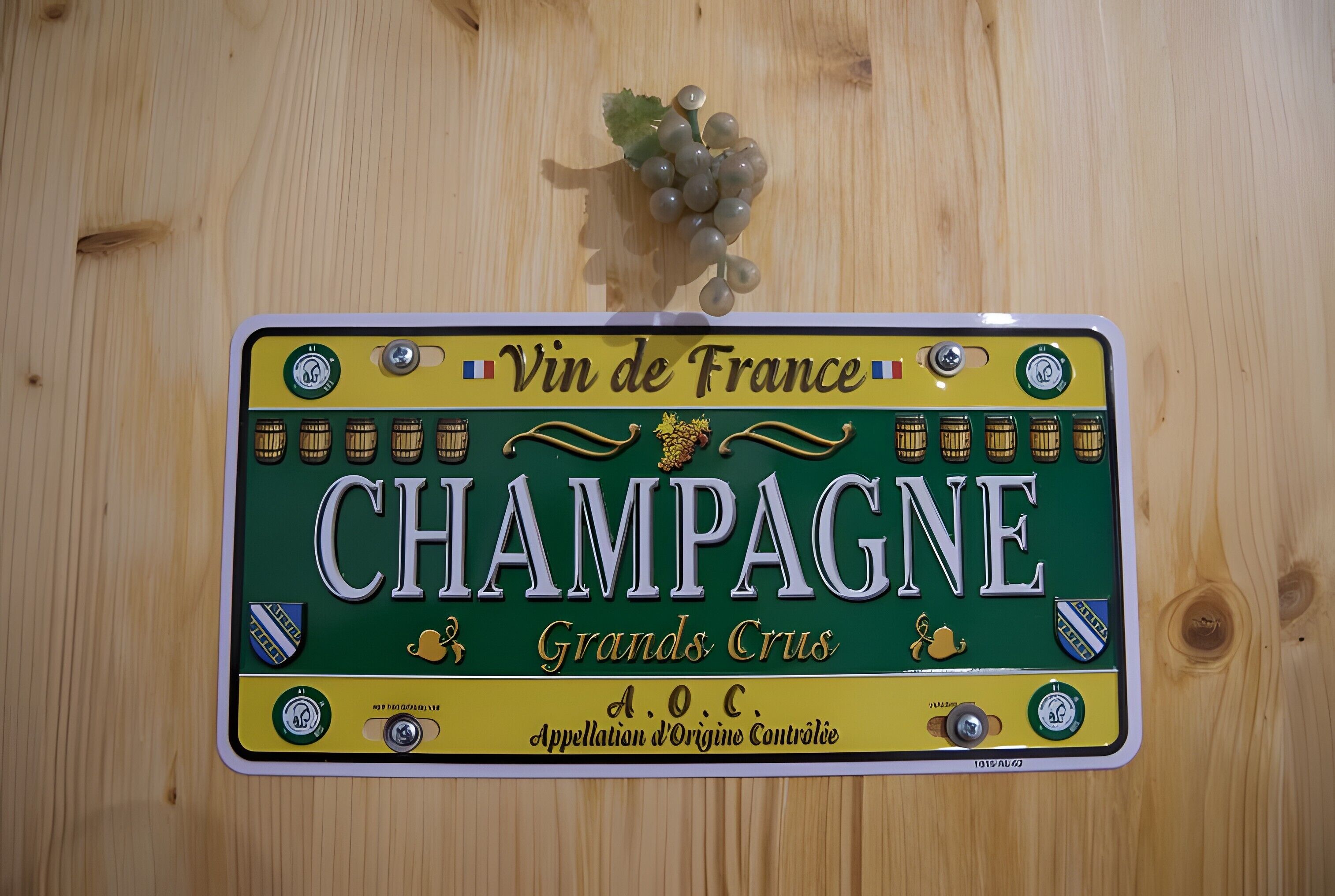 Een houten wand met een decoratief bord waarop 'CHAMPAGNE' en de tekst 'Vin de France' staan.