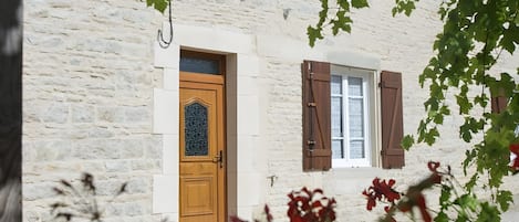 A stone building with a wooden door and window shutters.