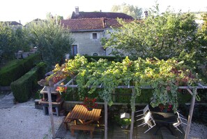Une pergola en bois, ornée de plantes grimpantes, avec une table et des chaises en dessous.