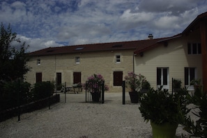 A building with a stone facade, multiple windows, and a gravel courtyard.