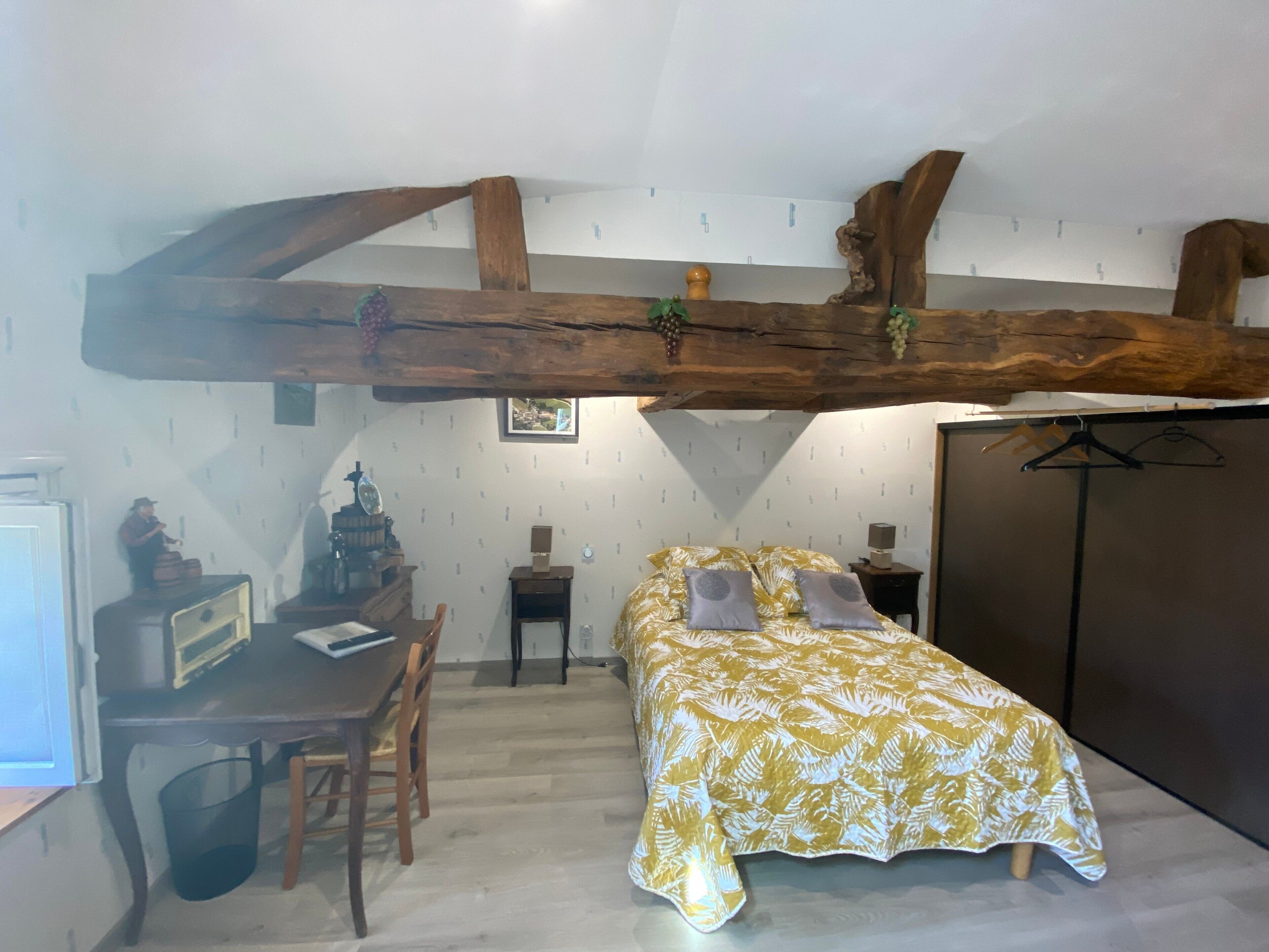 A bedroom with a bed, a desk, and a wardrobe.