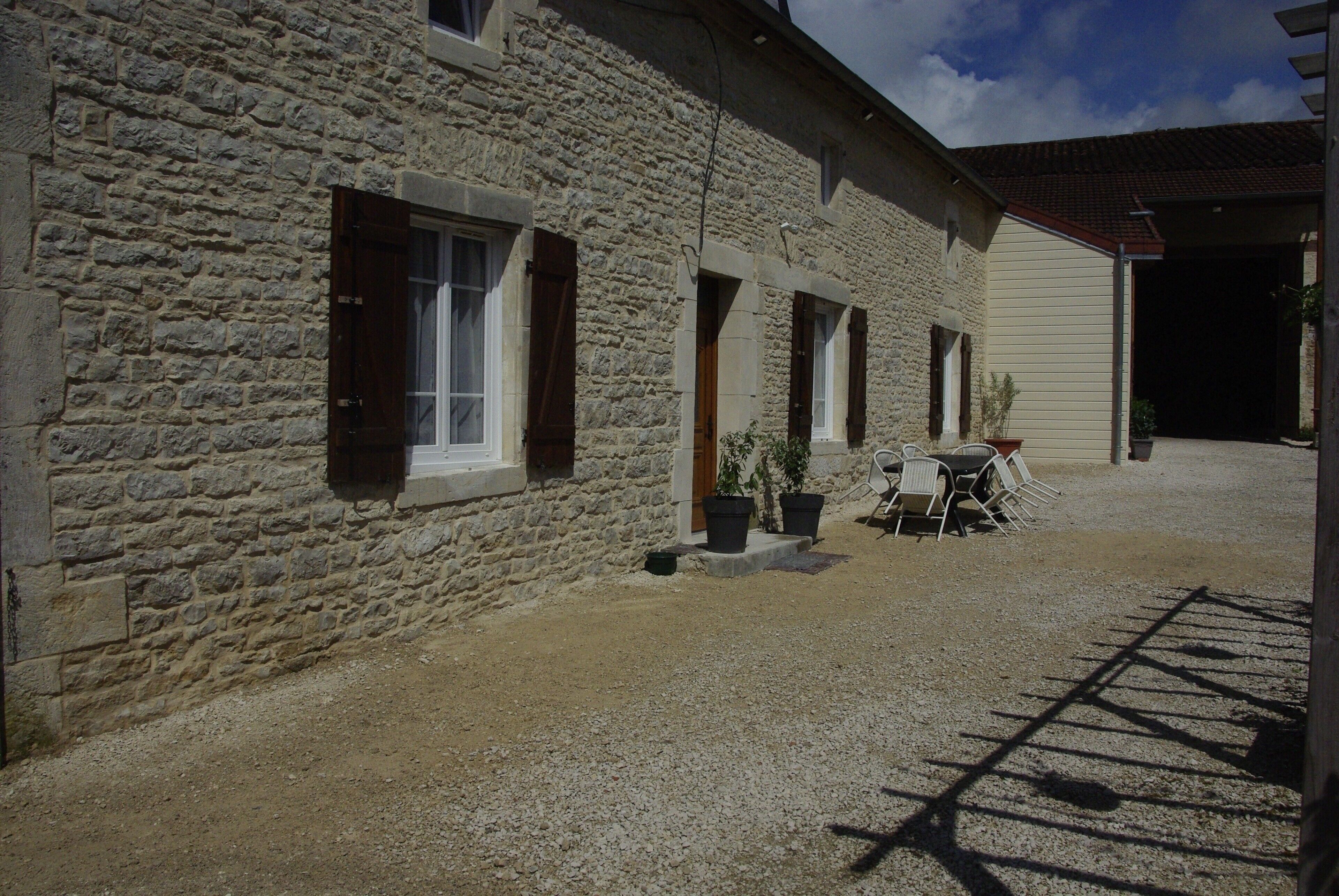 A stone building with multiple windows and a gravel driveway.