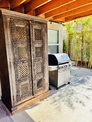 Une terrasse extérieure agrémentée d’une porte en bois décorative et d’un barbecue.