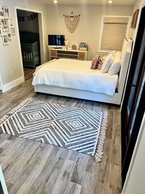 Une chambre à coucher avec un lit, une télévision, une commode et un tapis à motifs.