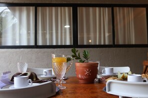 A breakfast setup with a table, a pitcher of orange juice, a small potted plant, and various breakfast items. - MHV Milagres - Lanai 06 (São Miguel dos Milagres)
