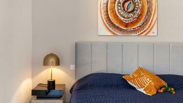 Ein Schlafzimmer mit einem Bett, einem Nachttisch mit Lampe und einem Wandbild.