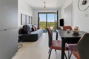 A modern living space with a sofa, dining table, chairs, and a television.