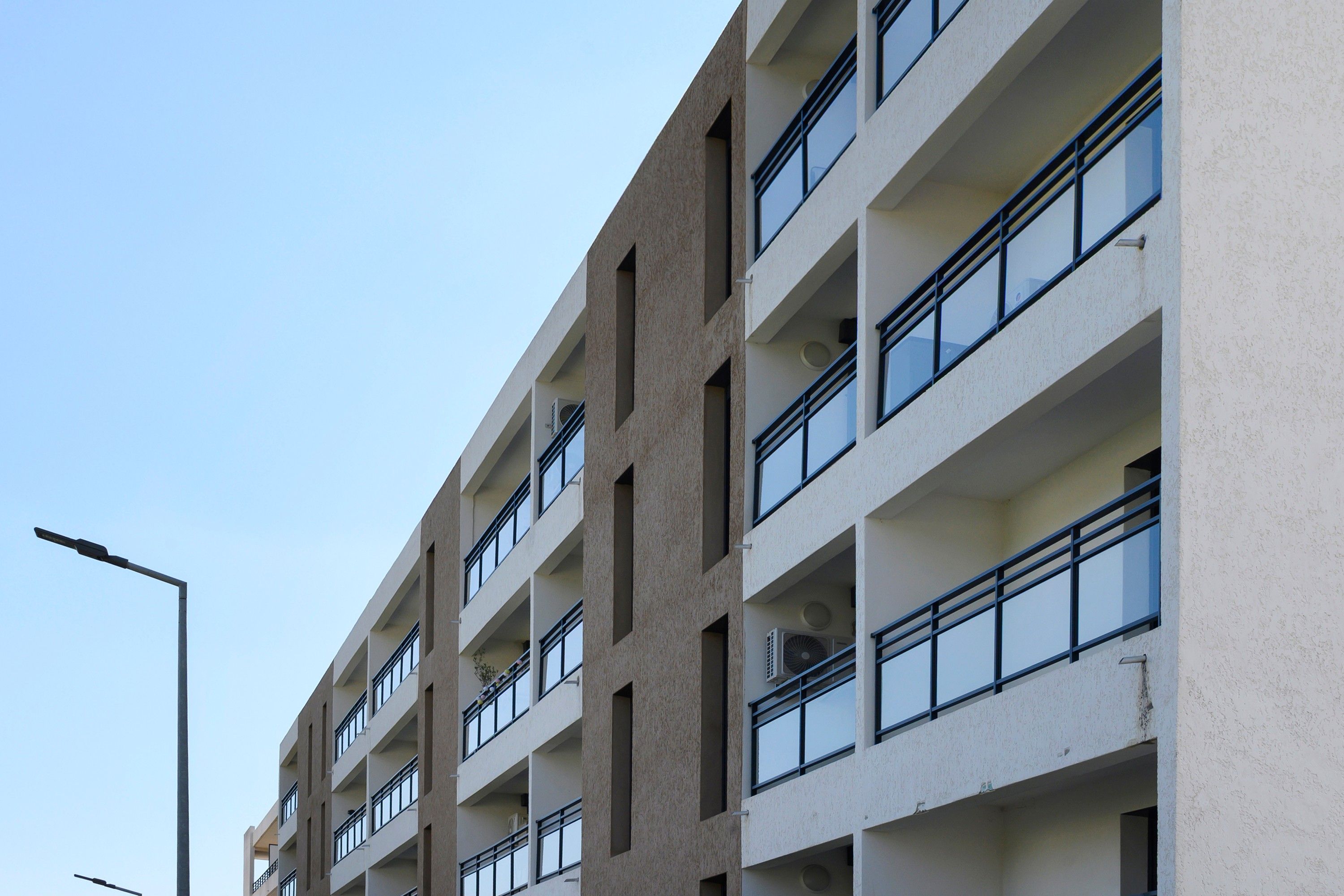 Ein mehrstöckiges Gebäude im modernen architektonischen Stil, mit Balkonen und großen Fenstern.