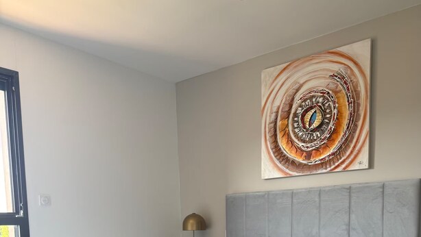A modern bedroom with a large bed, a headboard, a floor lamp, and a wall art piece.