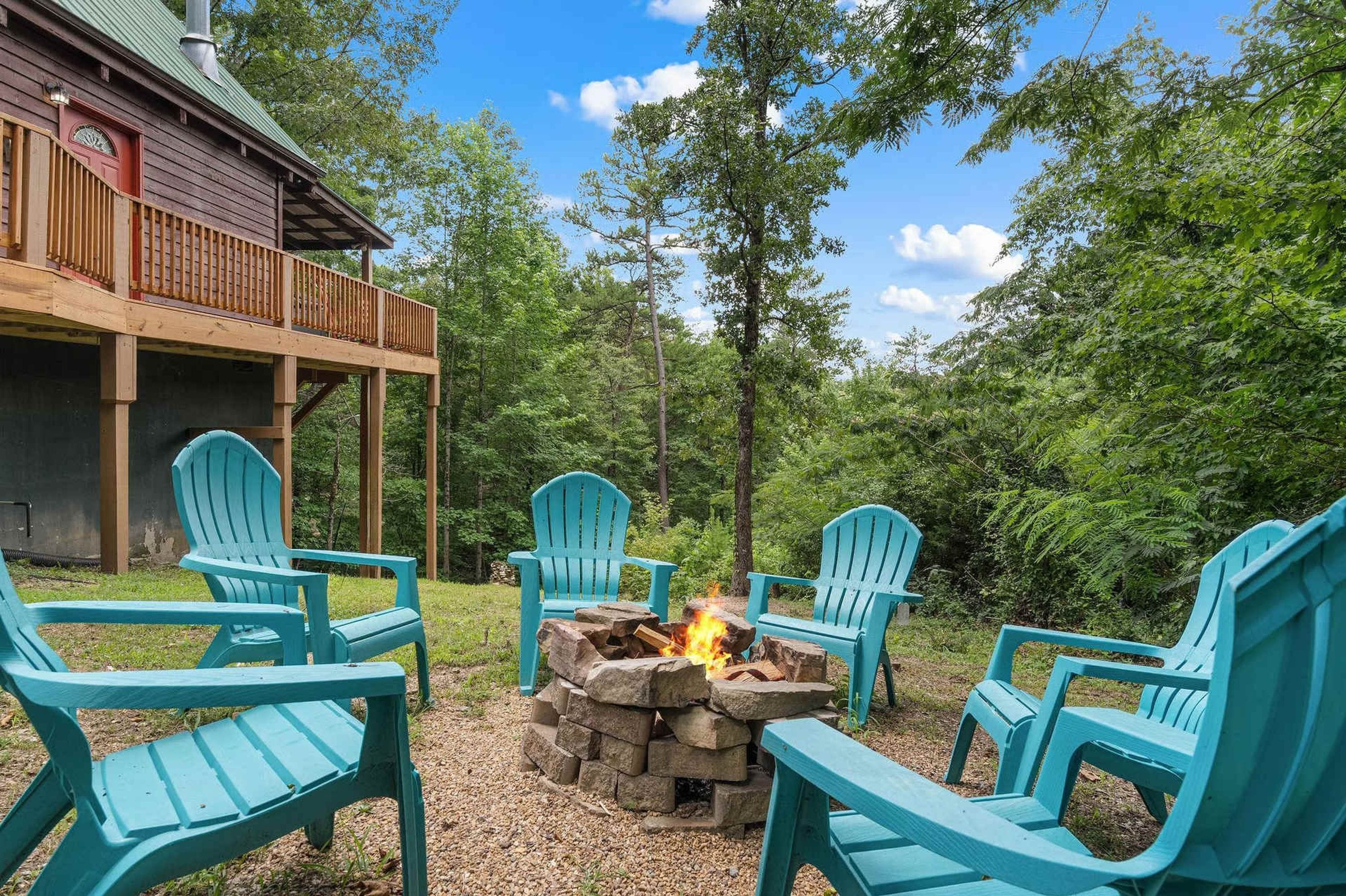 A wooden deck with outdoor seating and a stone fire pit.