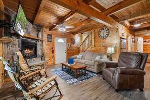 Ein gemütliches Blockhaus-Interieur mit Kamin aus Stein, Holzmöbeln, einer Uhr und einer Treppe.