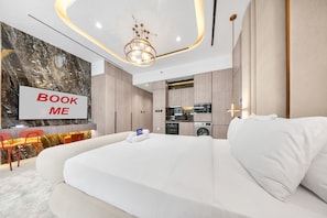 Ein modernes Hotelzimmer mit einem großen Bett, einem Fernseher, einer Minibar und einer integrierten Küche.