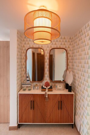 Ein Badezimmer-Waschtisch mit Spiegel, einem Holzkorpus und einer Deckenleuchte.