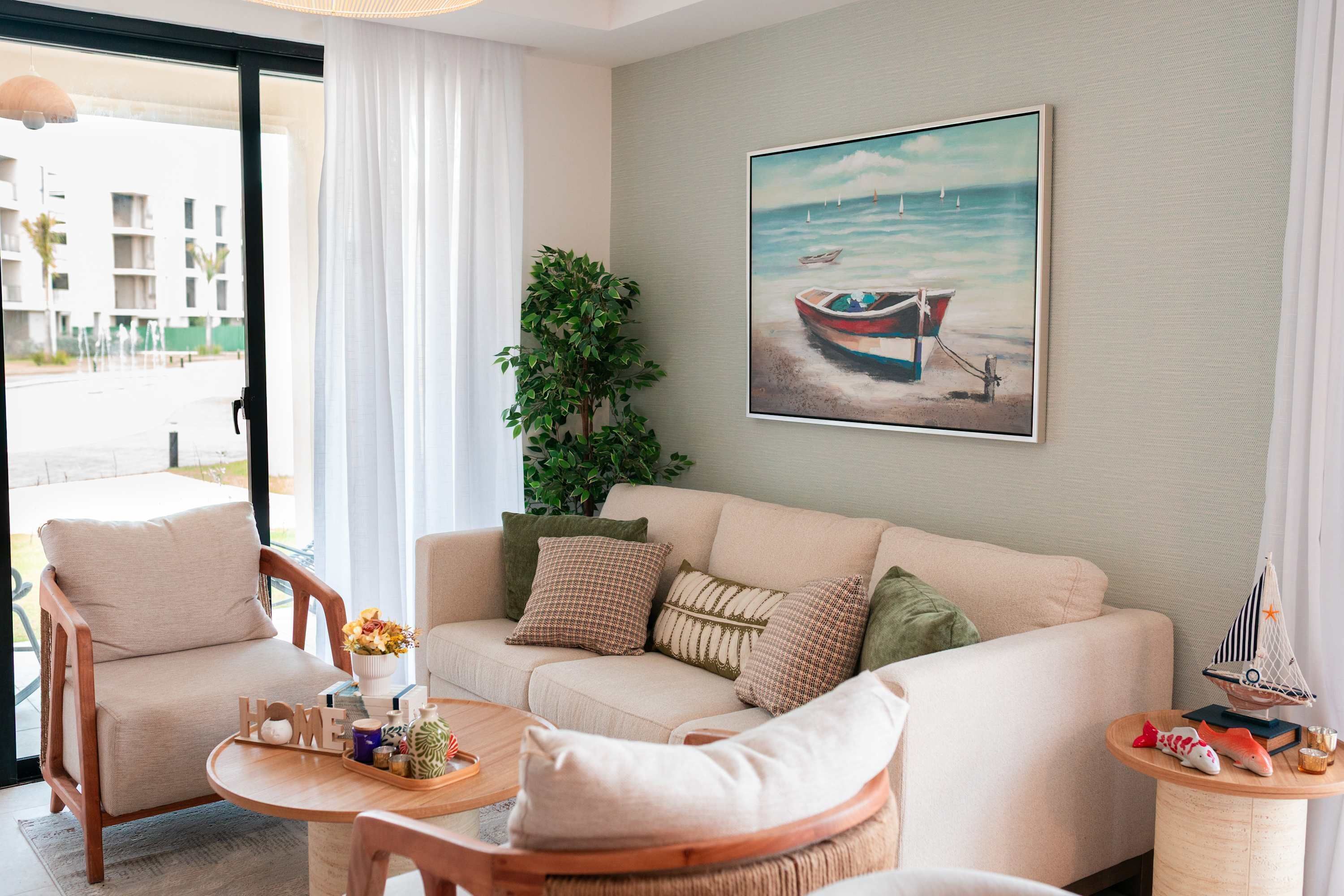 A living room with a sofa, armchairs, a coffee table, and a painting of a boat on the wall.